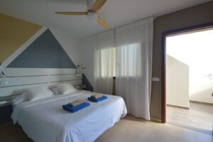 Dormitorio principal con detalle de cristalera y ventilador de techo del apartamento en planta baja de la urbanización Cotillo Mar