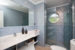 Otro Baño completo con detalle de mampara y lavabos de color blanco del chalet de lujo en Corralejo