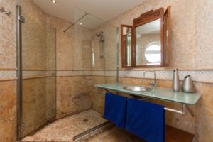 Baño completo con detalle de mampara y lavabos de cristal transparente del chalet de lujo en Corralejo