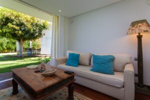Salón con detalle de sofás y cristalera con vista al jardín del chalet de lujo en Corralejo