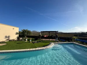 Perspectiva del jardín, piscina y fachada de la Villa en calle del jable de Lajares.