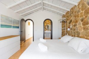 Dormitorio con detalle de vigas de madera blanca de la calle central de Lajares, Fueteventura