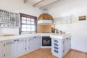 Perspectiva de la cocina y detalles de muebles blancos de la villa de la calle central de Lajares, Fueteventura