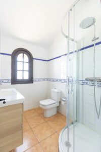 Baño completo decoración en blanco y madera clara de la villa de la calle central de Lajares, Fueteventura
