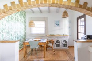 Perspectiva de la cocina con detalle de lamparas de la cocina con arco separador de piedra de la villa de la calle central de Lajares, Fueteventura