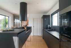 Cocina de diseño minimalista con acabados en madera y tono oscuro en encimeras, diseñada por Innova Home en Villa Gaia.