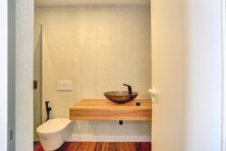 Baño acabados de grifos en color negro y lavabo en cristal oscuro transparente de los apartamentos de planta alta del edificio de 4 apartamentos en El Cotillo