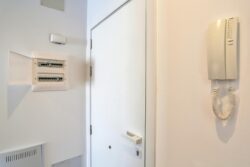 Puerta de entrada de la calle con detalle de cuadro de luces de los apartamentos de planta alta del edificio de 4 apartamentos en El Cotillo