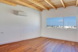 Salón con suelo de tarima de madera y vigas de madera en techo de los apartamentos de planta alta del edificio de 4 apartamentos en El Cotillo
