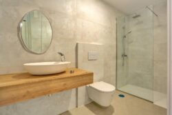 Baño completo, espejo, lavabo, sanitarios y plato de ducha de los apartamentos de planta baja del edificio de 4 apartamentos en El Cotillo