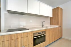 Cocina acabado mobiliario en color madera clara y blancos de los apartamentos de planta baja del edificio en El Cotillo