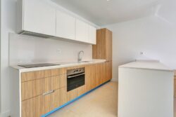 Cocina acabado mobiliario en color madera clara y blancos de los apartamentos de planta baja del edificio en El Cotillo